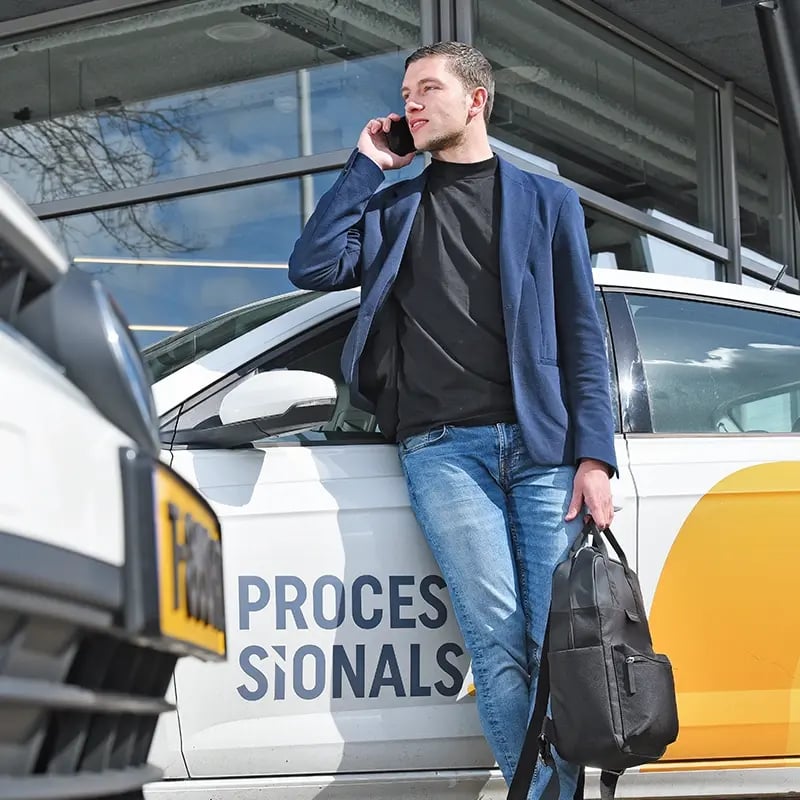 Corstiaan staat bij de Processionals auto te bellen