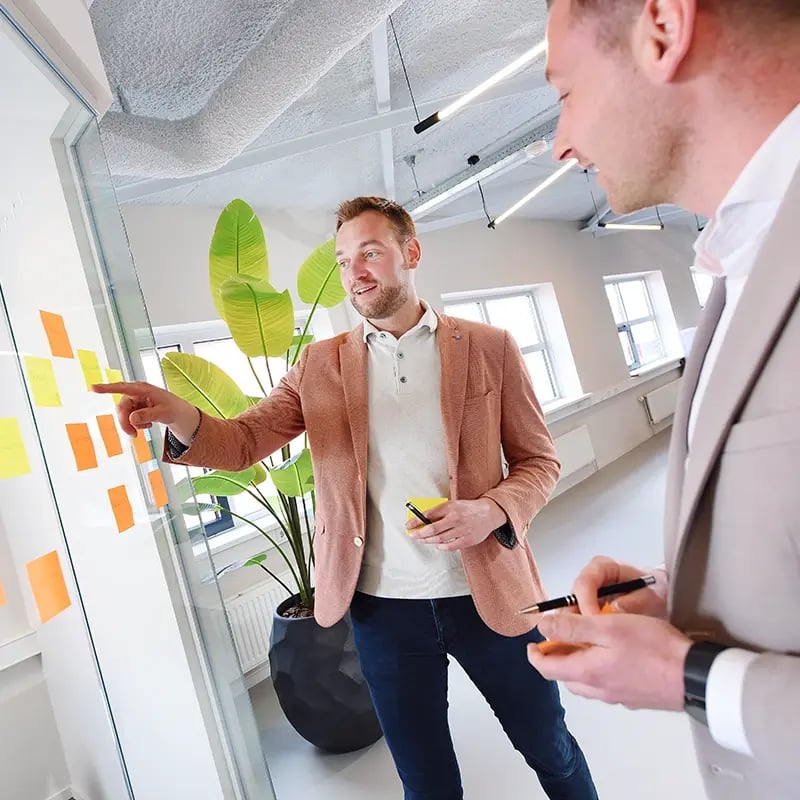 Michael en Dennis vergaderen bij het raam met post-its